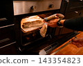 Placing homemade pizza in the oven for baking 143354823