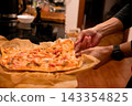 Removing freshly baked homemade pizza from the baking tray 143354825