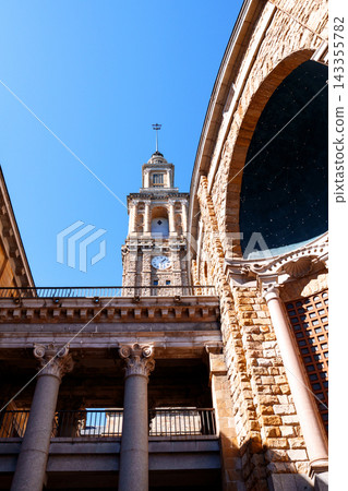 Architectural view of Laboral Ciudad de la Cultura in Gijon (Asturias), Spain. Monumental historic complex featuring a stone facade, massive arch and classical columns with Corinthian capitals Architectural view of Laboral Ciudad de la Cultura in Gijon (Asturias), Spain. Monumental historic complex featuring a stone facade, massive arch and classical columns with Corinthian capitals 143355782