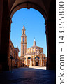 Laboral Ciudad de la Cultura tower and church seen through a stone arch against a clear blue sky. 143355800