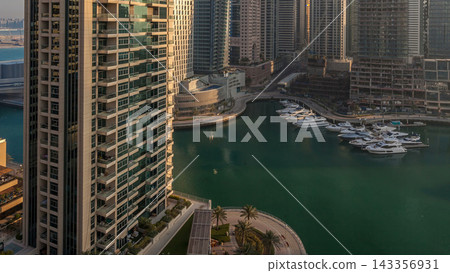 View of modern skyscrapers shining in sunrise lights timelapse in Dubai Marina in Dubai, UAE. View of modern skyscrapers shining in sunrise lights timelapse in Dubai Marina in Dubai, UAE. 143356931