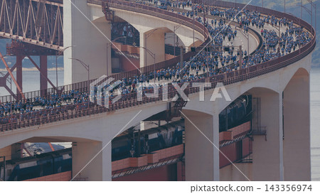 Running Lisbon half marathon crossing the 25 of April bridge over the Tagus river aerial view from above. Running Lisbon half marathon crossing the 25 of April bridge over the Tagus river aerial view from above. 143356974