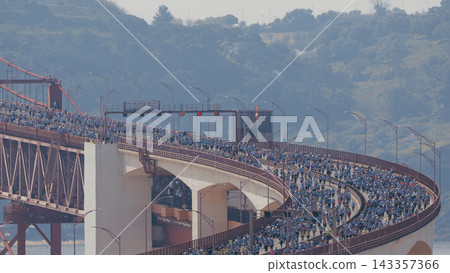 Running Lisbon half marathon crossing the 25 of April bridge over the Tagus river aerial view from above. Running Lisbon half marathon crossing the 25 of April bridge over the Tagus river aerial view from above. 143357366