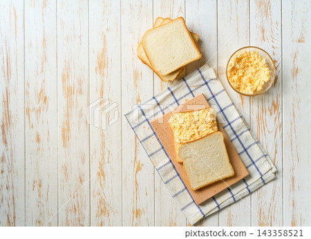 Homemade egg sandwich for breakfast on a white table, top view. Homemade egg sandwich for breakfast on a white table, top view. 143358521