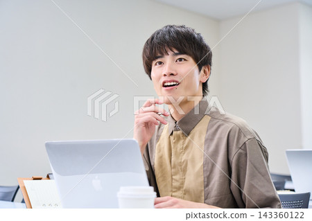 一位二十多歲的男子打開電腦，開始學習。 143360122