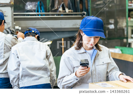 A group of female workers using handheld terminals to manage products in a factory A group of female workers using handheld terminals to manage products in a factory 143360261