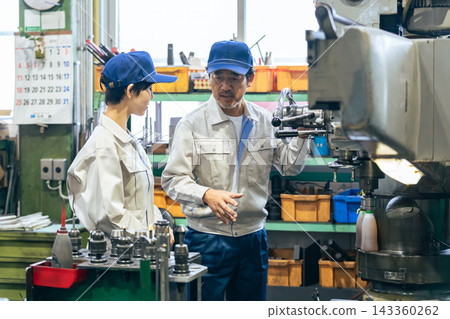 A group of workers operating machine tools in a factory A group of workers operating machine tools in a factory 143360262