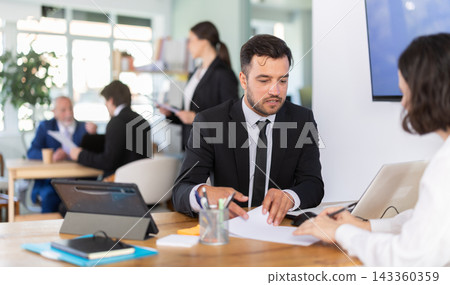 Bank manager talking with female client in office Bank manager talking with female client in office 143360359