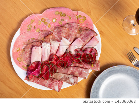 Slices of butifarra and smoked sausage dished up in a service plate on laid restaurant table Slices of butifarra and smoked sausage dished up in a service plate on laid restaurant table 143360368