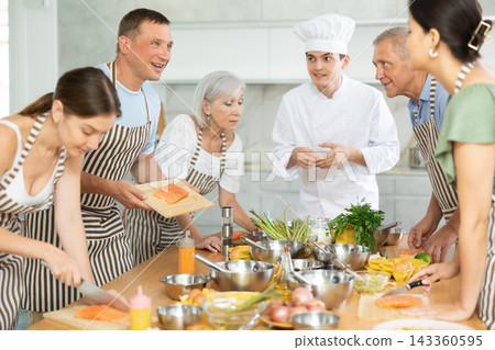 Cheerful man communicating friendly to participants of culinary class Cheerful man communicating friendly to participants of culinary class 143360595