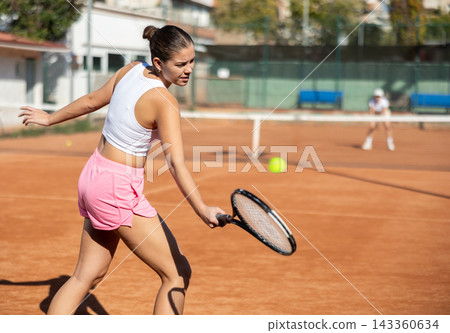 Young woman playing tennis against older woman Young woman playing tennis against older woman 143360634