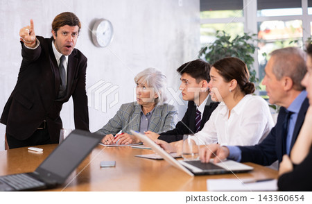 Dissatisfied manager reprimanding subordinates during work meeting Dissatisfied manager reprimanding subordinates during work meeting 143360654