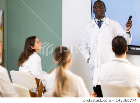 Adult male doctor presenting with remote control in meeting room Adult male doctor presenting with remote control in meeting room 143360774
