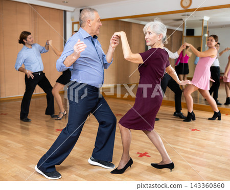 Couple of mature dancers rehearsing ballroom dances in dance studio Couple of mature dancers rehearsing ballroom dances in dance studio 143360860