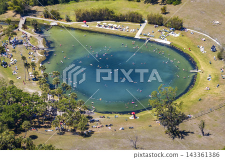 Crowd of people enjoying warm salty spring, floating and swimming in mineral-rich water associated with healing, relaxation, and spa tourism. Warm Mineral Springs in North Port, Florida, USA. Crowd of people enjoying warm salty spring, floating and swimming in mineral-rich water associated with healing, relaxation, and spa tourism. Warm Mineral Springs in North Port, Florida, USA. 143361386
