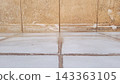 Grimy brown tile wall meets a white floor stained with mold and mineral deposits 143363105