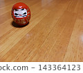 A cute, auspicious red Daruma doll placed on a wooden table. 143364123