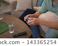 Couple relaxes at home playing video game together with controller and snacks on coffee table 143365254