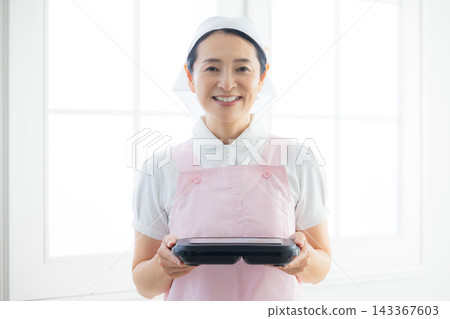身穿圍裙、手提便當盒的女士。 身穿圍裙、手提便當盒的女士。 143367603