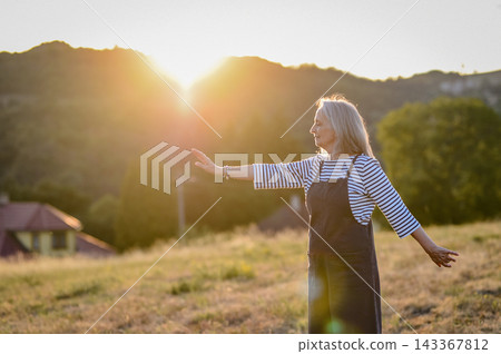 Senior woman practicing meditation outdoors in peaceful countryside. Senior woman practicing meditation outdoors in peaceful countryside. 143367812