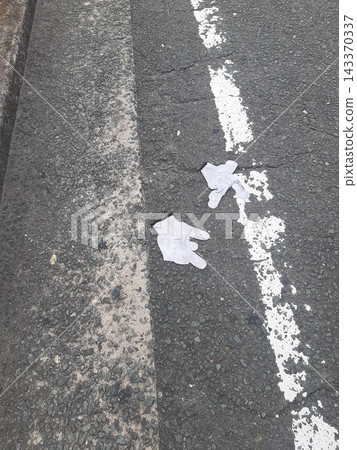 White gloves lying on the asphalt 143370337