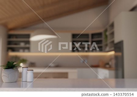 Close up of marble kitchen counter with plant and ceramic bottles with blurred cabinetry background. 143370554