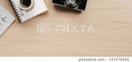 Top view of wooden desk setup with a laptop, earbuds, notebook and coffee cup with vintage camera. Top view of wooden desk setup with a laptop, earbuds, notebook and coffee cup with vintage camera. 143370569