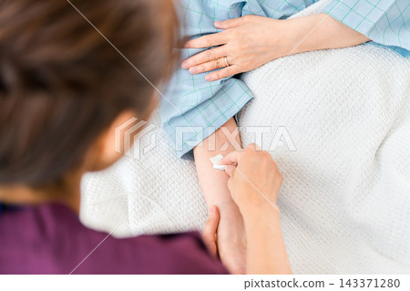 一名女護士在給住院病人注射、抽血或輸液前,用乙醇消毒病人的手臂。 一名女護士在給住院病人注射、抽血或輸液前,用乙醇消毒病人的手臂。 143371280