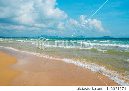 Tropical beach at Haitang Bay in Sanya Hainan with golden sand, ocean waves, and blue sky. Perfect summer vacation destination Tropical beach at Haitang Bay in Sanya Hainan with golden sand, ocean waves, and blue sky. Perfect summer vacation destination 143371574