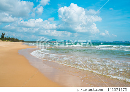 Sanya Hainan travel destination view. Sand beach, ocean waves, and cityscape on the horizon at summer day in Haitang Bay 143371575