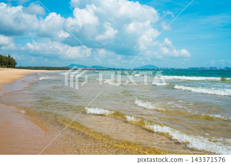 Tropical beach at Haitang Bay in Sanya Hainan with golden sand, ocean waves, and blue sky. Perfect summer vacation destination Tropical beach at Haitang Bay in Sanya Hainan with golden sand, ocean waves, and blue sky. Perfect summer vacation destination 143371576