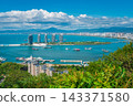 Coastal panorama of Sanya cityscape, blue bay, and iconic Phoenix Island buildings from Luhuitou mountain park, Hainan resort 143371580