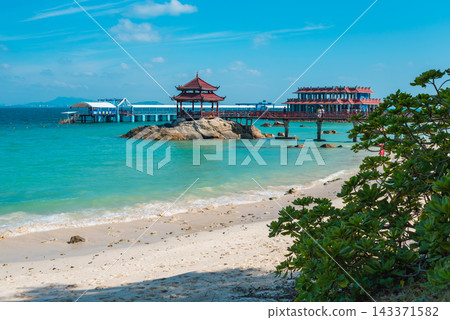 Tropical beach view with bridge, pagoda, rocks, and blue ocean on Pirate Island Wuzhizhou in Sanya Hainan. Summer travel destination 143371582