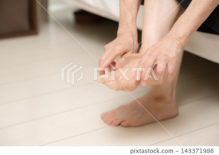 An elderly Japanese woman putting on stockings, her feet, getting dressed, getting ready to go out (faceless). An elderly Japanese woman putting on stockings, her feet, getting dressed, getting ready to go out (faceless). 143371986