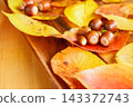 Acorns lined up on fallen autumn leaves 143372743