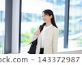一位女商人面帶微笑地站在辦公大樓的走廊上。 143372987