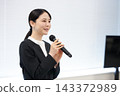 一位女商人手持麥克風，微笑地進行演講。 143372989