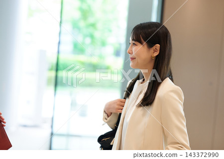 A businesswoman smiling and chatting in the lobby of an office building. 143372990