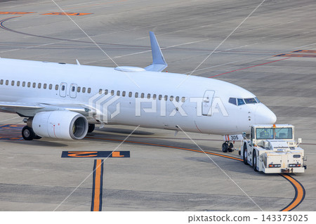 A passenger plane and towing vehicle prepare for departure. A passenger plane and towing vehicle prepare for departure. 143373025