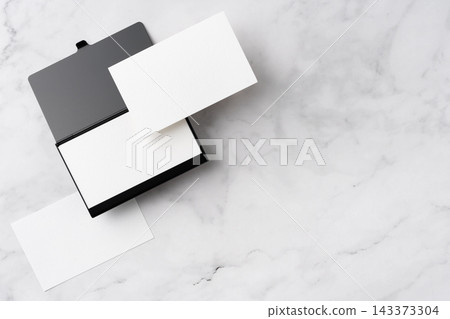 Blank white business cards and open black aluminum card holder on white marble background, top view flat lay with copy space Blank white business cards and open black aluminum card holder on white marble background, top view flat lay with copy space 143373304
