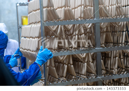 Rows of Fresh Sausages Hanging on Racks in Food Processing Factory 143373333