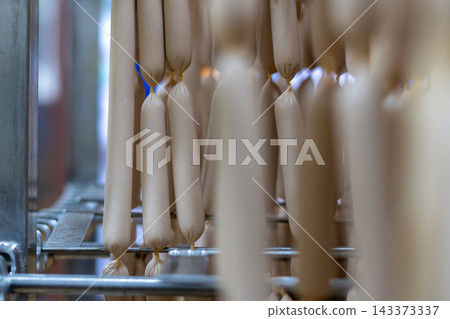 Rows of Fresh Sausages Hanging on Racks in Food Processing Factory Rows of Fresh Sausages Hanging on Racks in Food Processing Factory 143373337