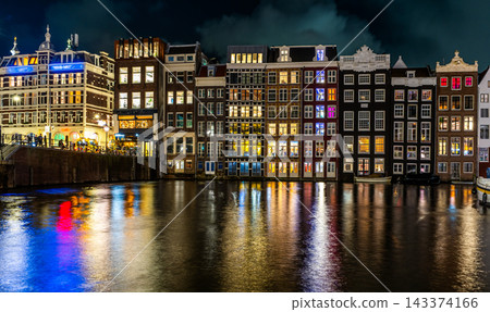 Amsterdam Netherlands night. Colorful houses canal water. Sightseeing Evening street architecture with lights in windows and lanterns. Old Building Amsterdam Netherlands night. Colorful houses canal water. Sightseeing Evening street architecture with lights in windows and lanterns. Old Building 143374166