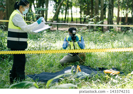 Investigator taking photo of evidence marker with camera at crime scene. Investigator taking photo of evidence marker with camera at crime scene. 143374231