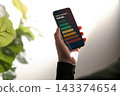 Hand holds a smartphone displaying an energy rating scale 143374654