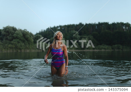 Active senior woman swimming in natural lake during indian summer. Active senior woman swimming in natural lake during indian summer. 143375094