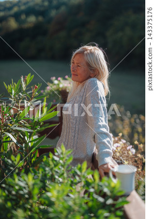 Mature woman having morning coffee on cozy cabin balcony. Mature woman having morning coffee on cozy cabin balcony. 143375176