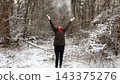 Happy adult woman throw up fresh snow and spinning under falling cloud of snowflakes at wood. Cheerful lady having fun in winter forest with joyful expression. Carefree female enjoy winter vacation 143375276
