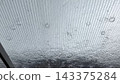 Heavy rain pouring on transparent plastic roof canopy. View of large raindrops and flow water stream smashing into corrugated polycarbonate sheet on rainy day. Serene and moody seasonal weather scene 143375284