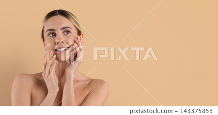 Young woman gently touching face with both hands against beige studio background Young woman gently touching face with both hands against beige studio background 143375853